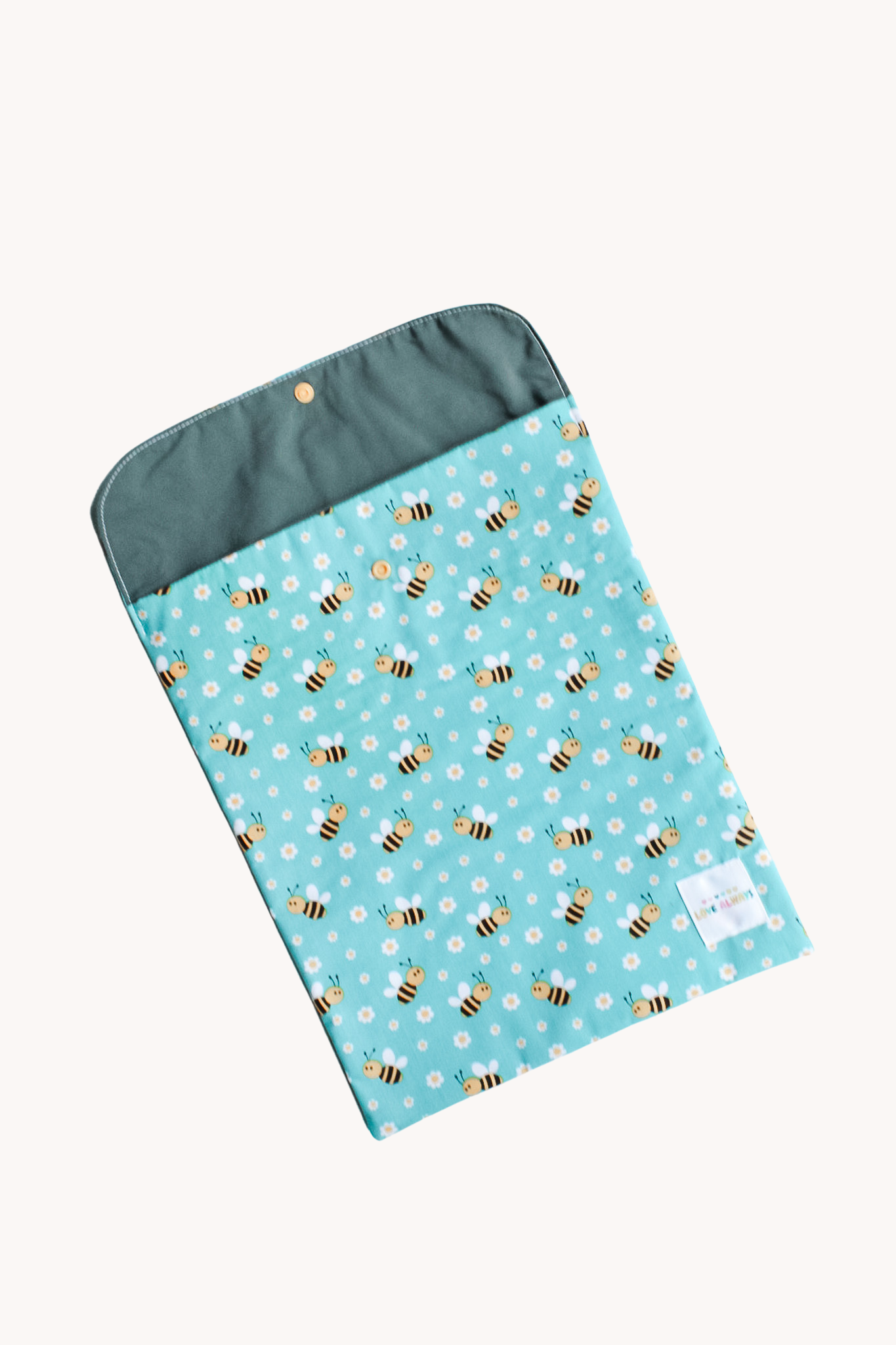 The Little Bees book bag with its flap open, showing the teal lining inside and the press stud