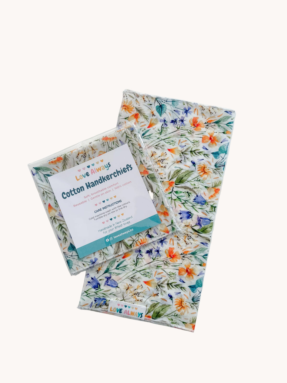 The Meadow Kiss cotton handkerchief with its Love Always Cotton Handkerchiefs packet — apricot and blue wildflowers with trailing green leaves on cream