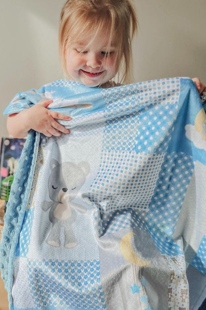 A toddler holding up a Love Always minky blanket, showing the size and the soft patchwork front
