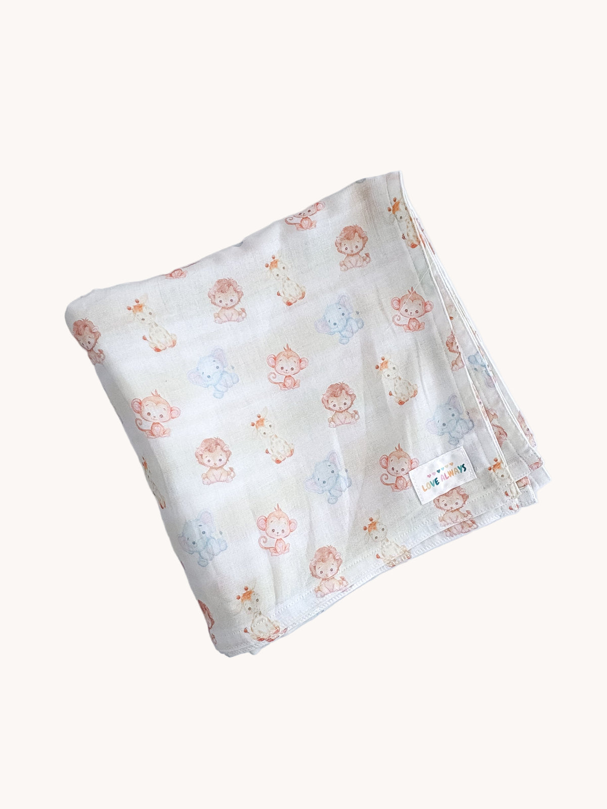 The Little Jungle muslin wrap folded flat, showing pale watercolour monkeys, elephants and giraffes on white